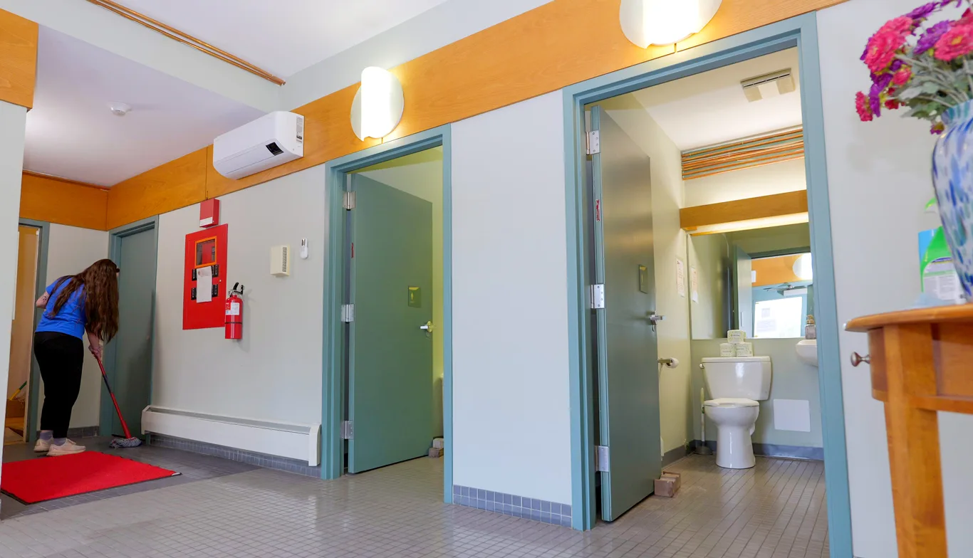 Cleaner wiping floors in a common area by bathrooms